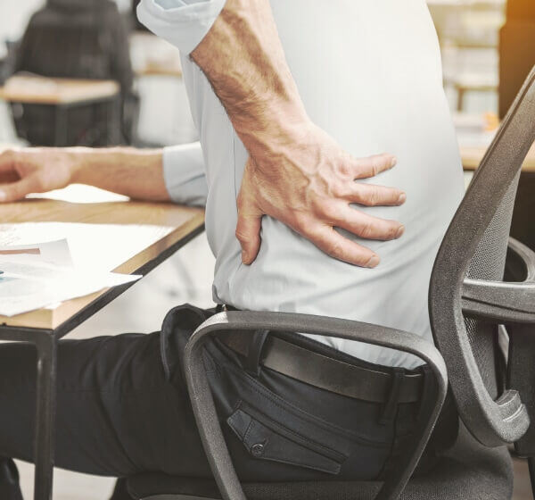 An office worker with a hand on a painful back