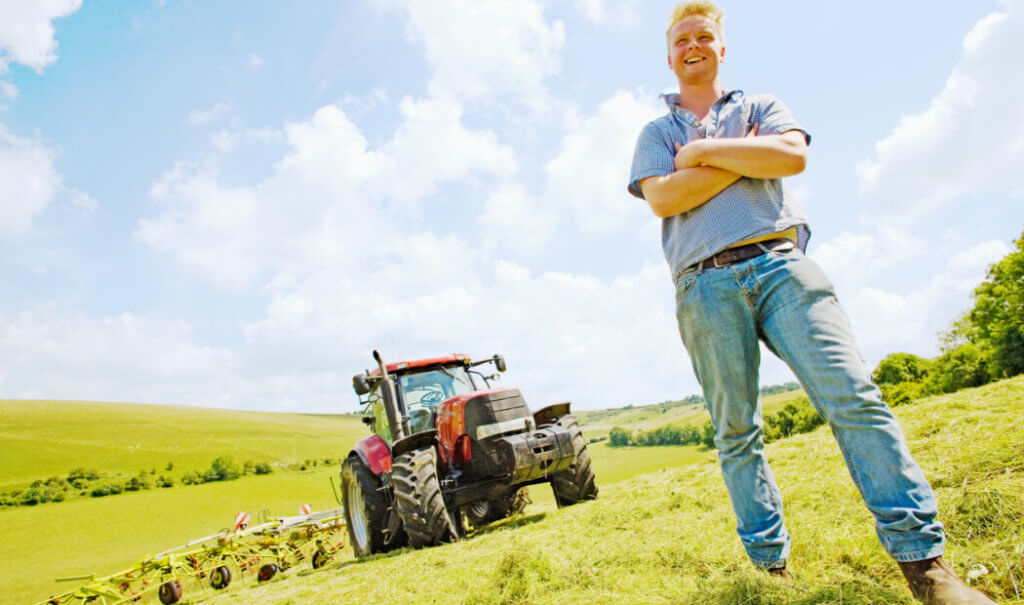 agricultural worker standing in field in front of tractor
