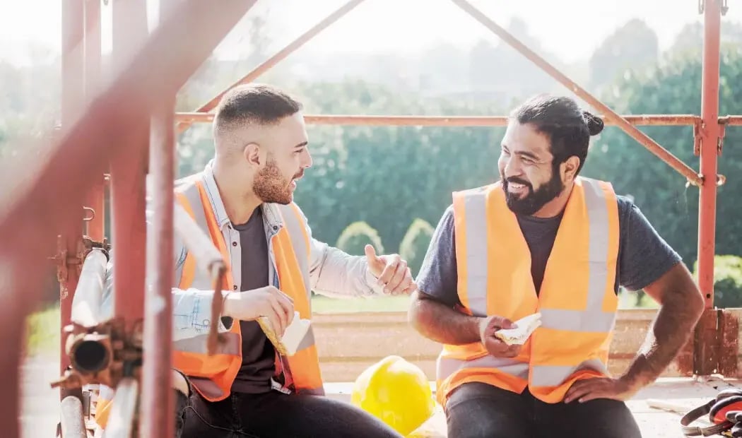two construction workers chatting on their lunch break two construction workers chatting on their lunch break