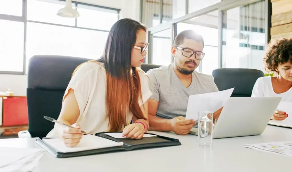 Financial services professionals reading paperwork and taking notes Financial services professionals reading paperwork and taking notes