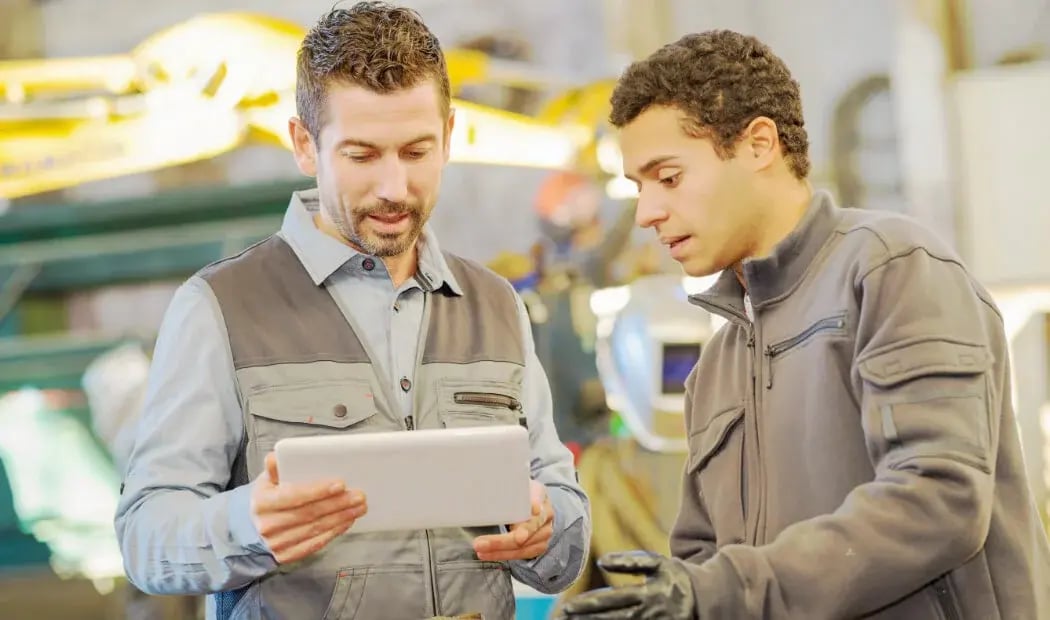 manufacturing workers looking at a tablet screen manufacturing workers looking at a tablet screen