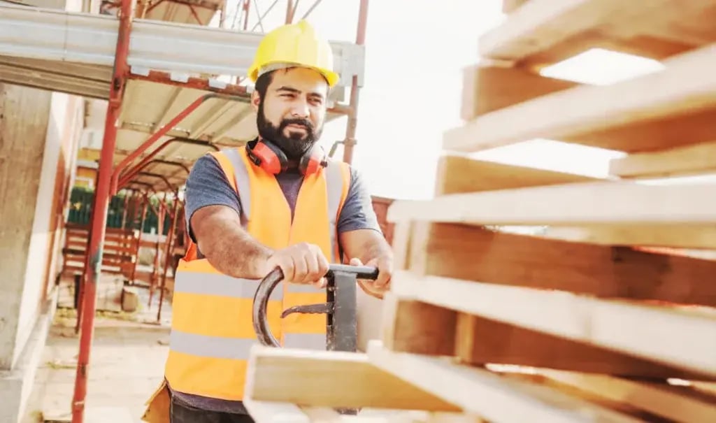 transport worker in PPE operating a pallet truck