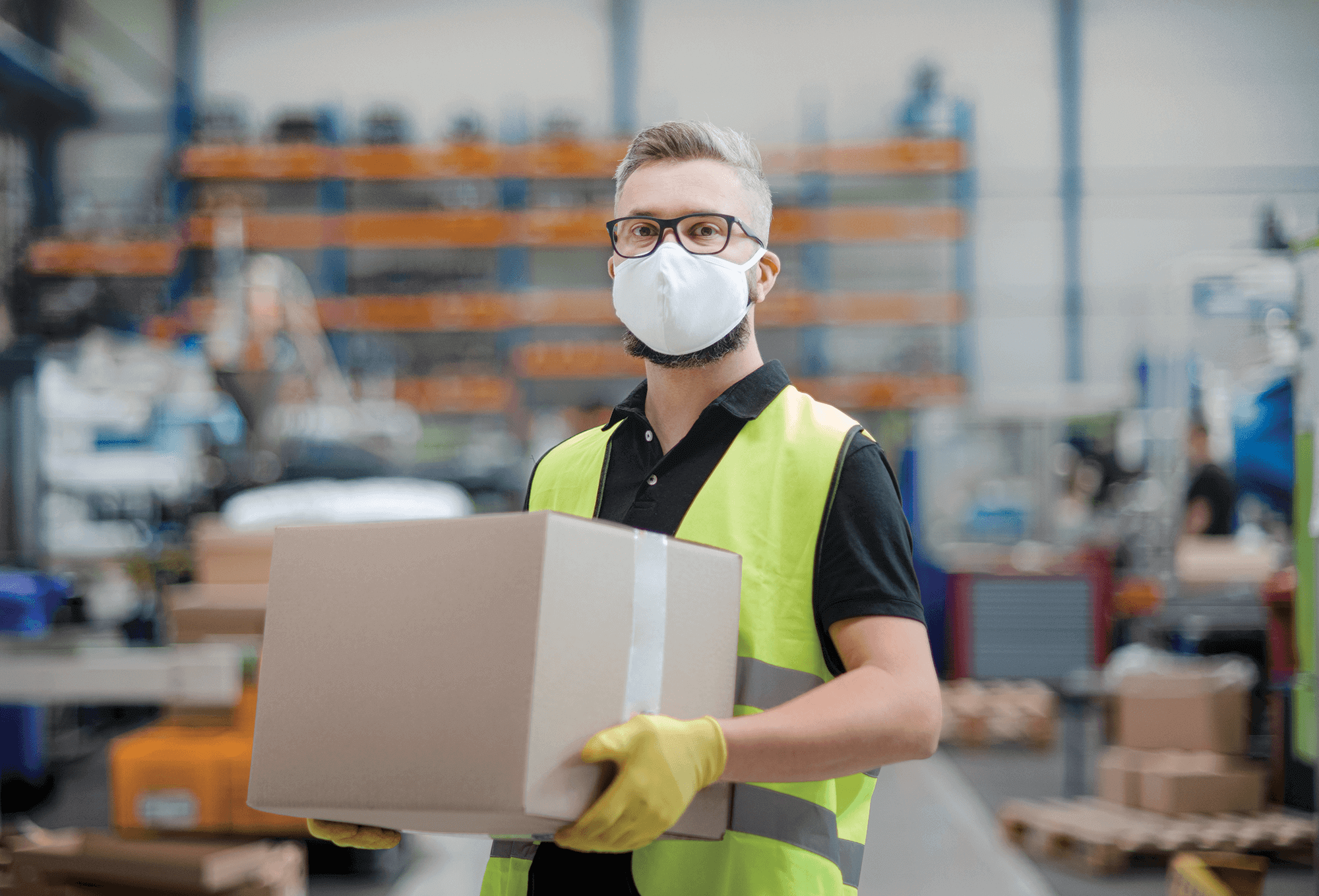 Man wearing a face mask carrying a box