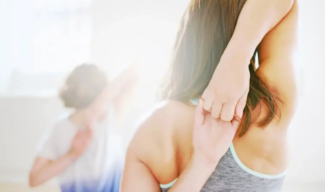 Women in gym gear with interlocked hands behind backs stretching triceps Women in gym gear with interlocked hands behind backs stretching triceps