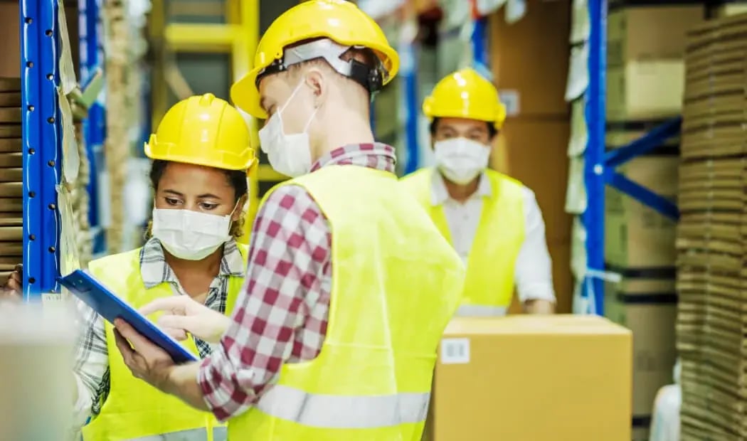 workers wearing PPE and masks in warehouse environment workers wearing PPE and masks in warehouse environment