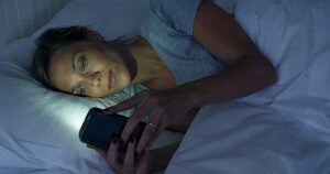 Someone using their phone in bed