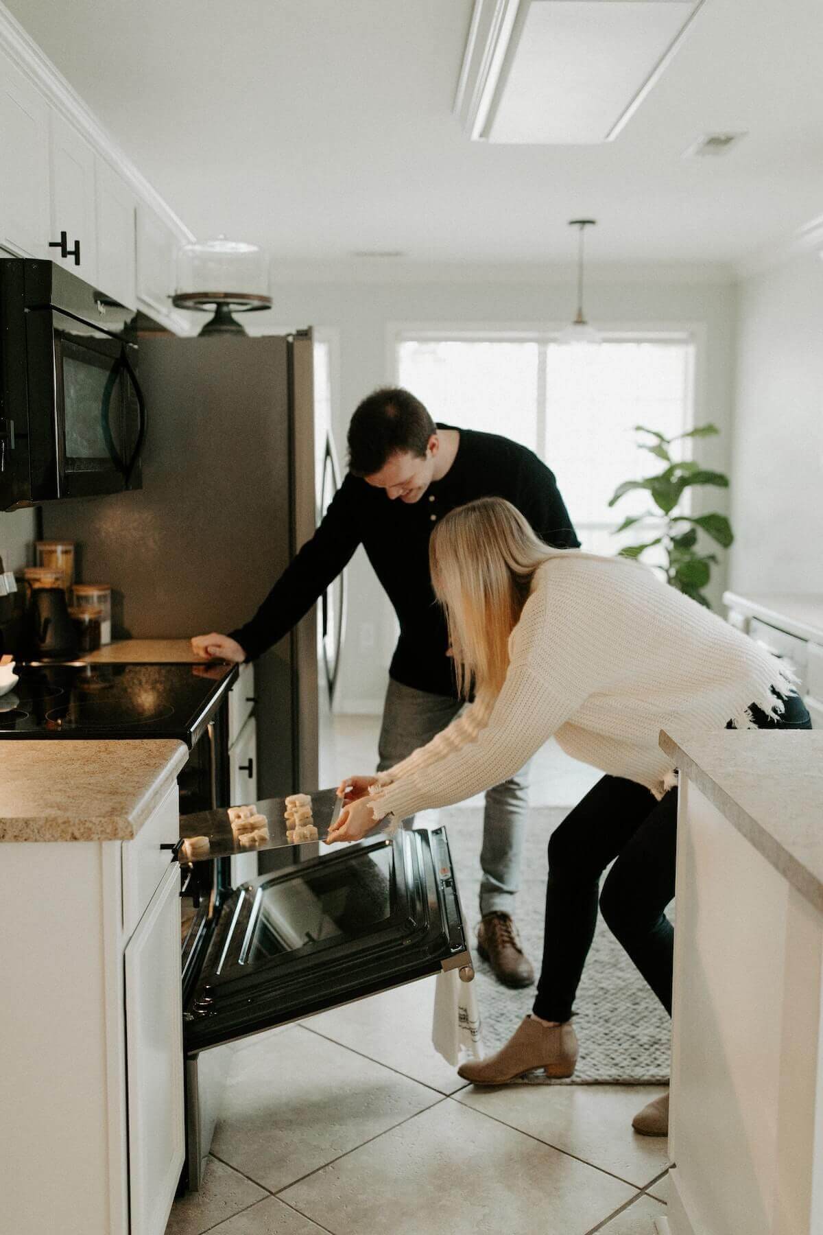 a couple putting some food in the oven