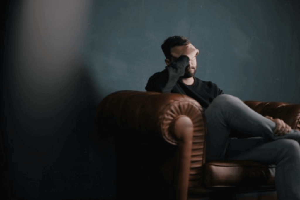 Man sat on a sofa with his head in his hand