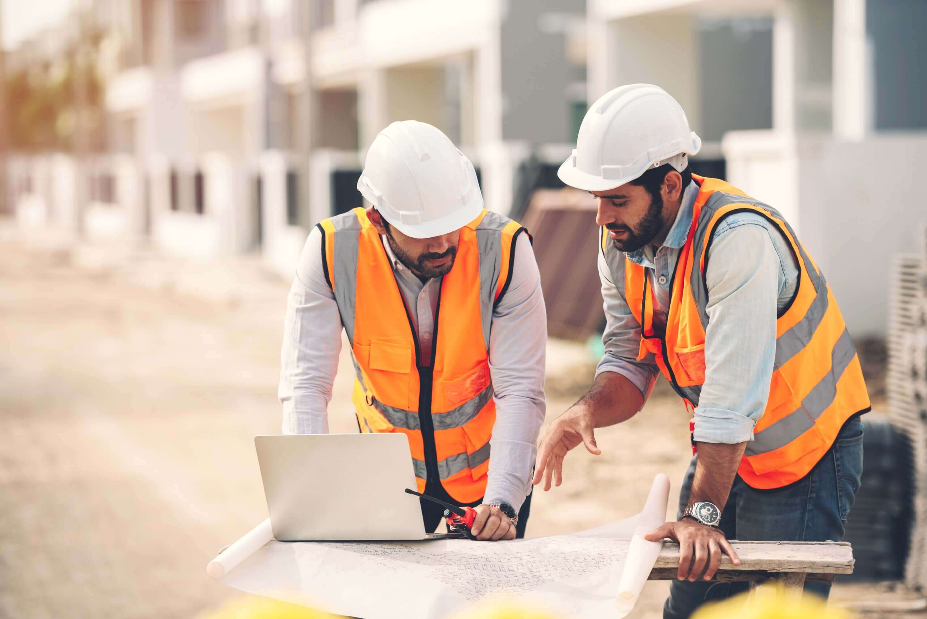 two construction workers in hi-viz looking at plans on-site