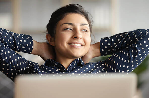 a happy smiling employee with hands behind head