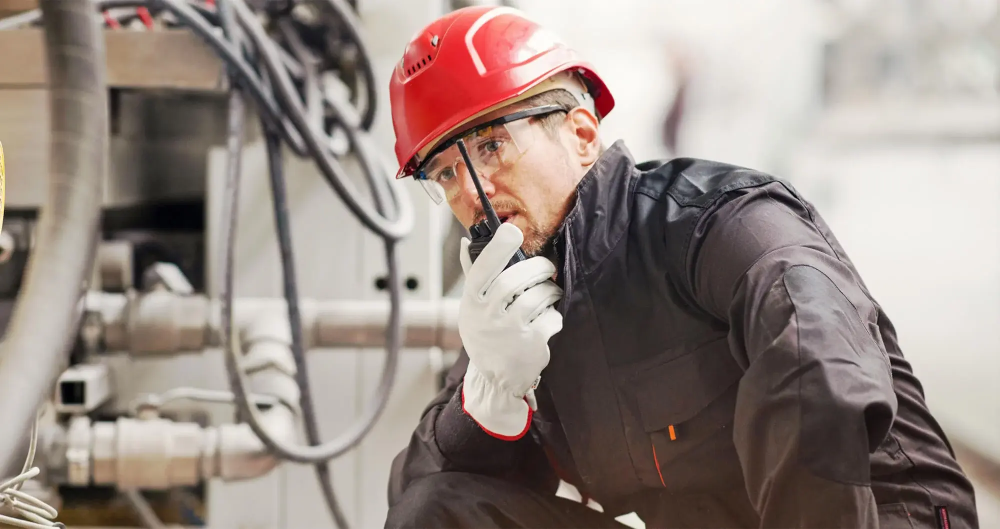 manufacturing worker wearing PPE talking in to a radio
