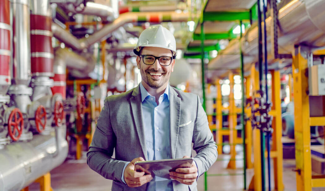 Energy industry employee wearing a hard hat and holding a hand-held tablet
