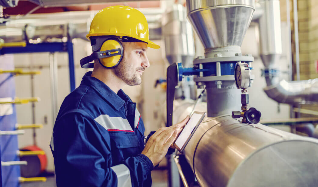 Energy industry employee wearing a hard hat and ear defenders