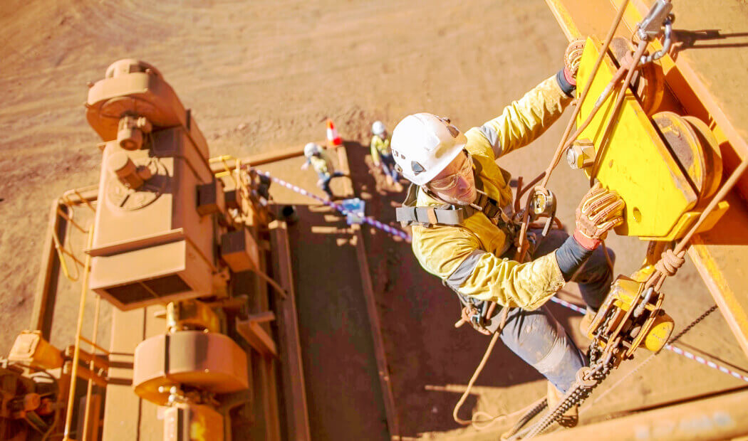 A mining rig operator working in a safety harness