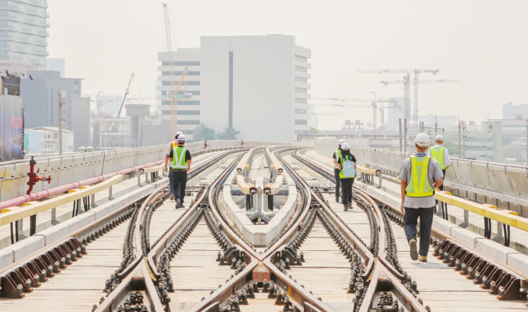 transport workers wearing PPE walking on train tracks