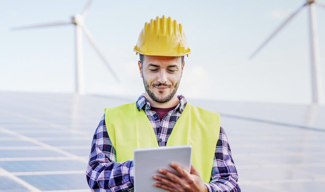 energy worker wearing PPE with tablet in hand