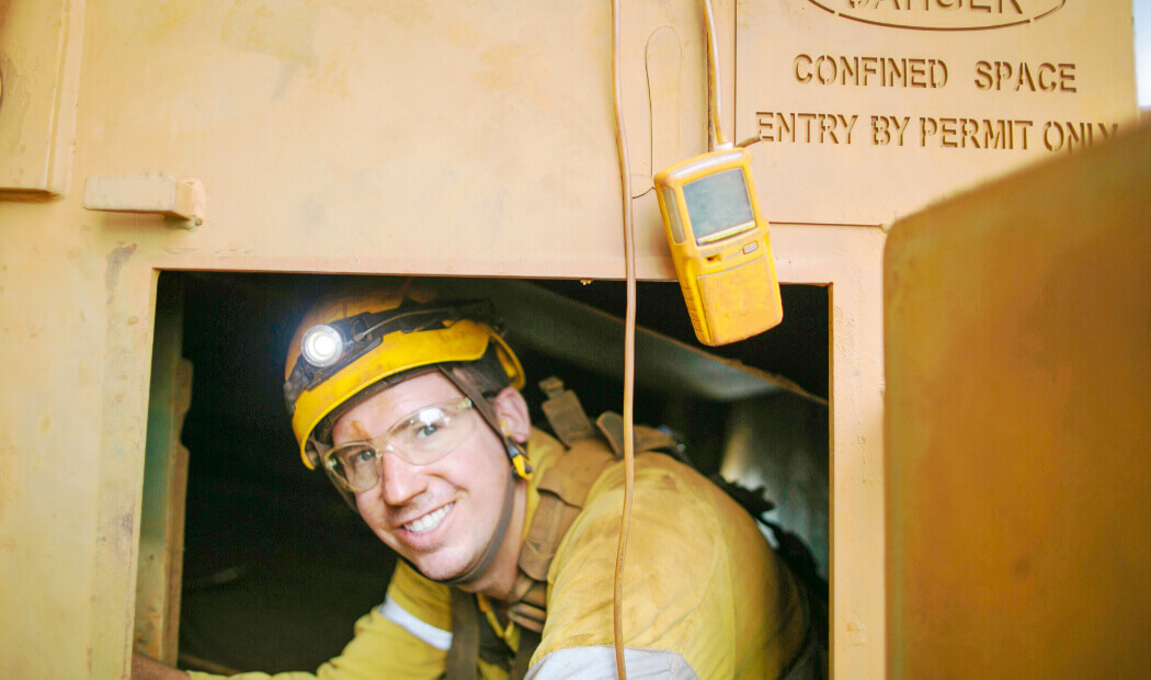 A FIFO worker wearing PPE and a head torch in a confined space