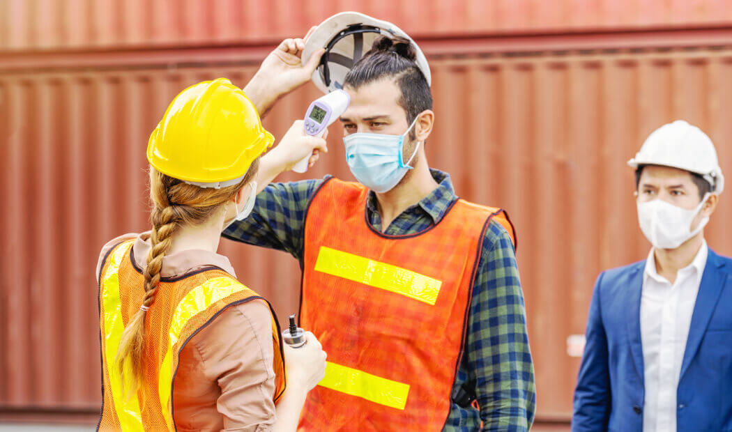 worker in PPE having temperature checked