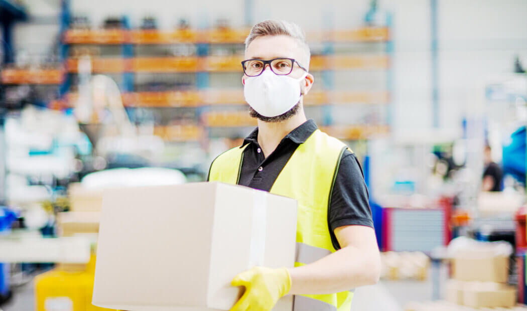 worker wearing a face mask carrying a box