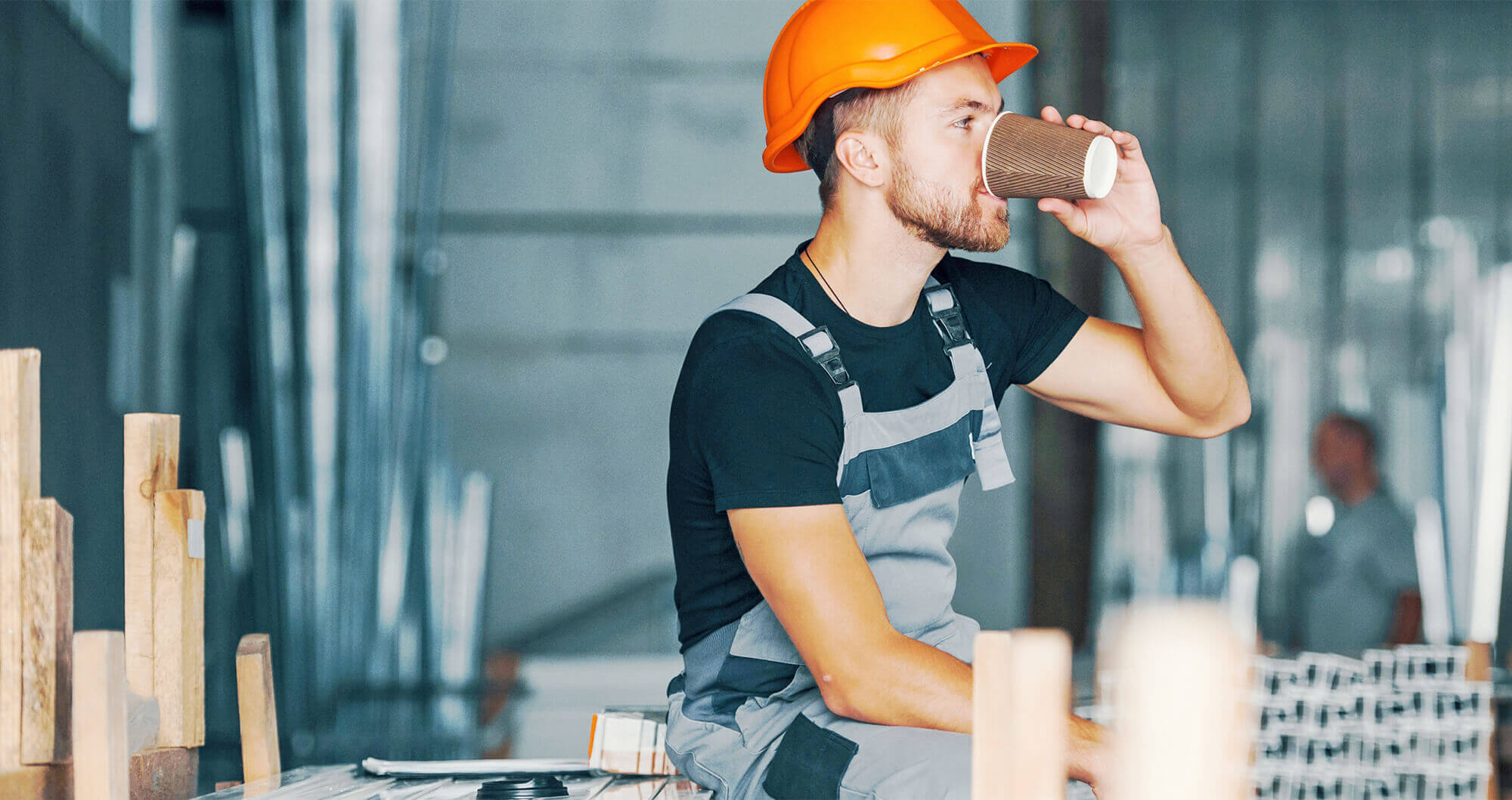 worker wearing a hard hat sat drinking coffee