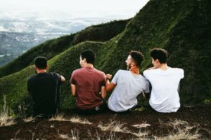 Four young men sitting at a hilltop viewpoint